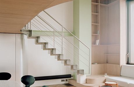 Modernist staircase with steel railing and built-in shelving in open-concept living space.