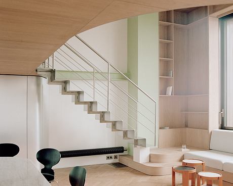 Modernist staircase with steel railing and built-in shelving in open-concept living space.