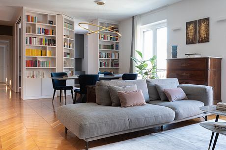 Modern living room with sofa, bookshelf, and dining area.