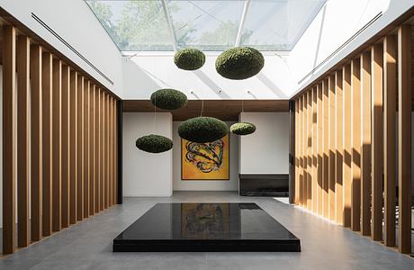 Minimalist interior design with suspended moss spheres, wood paneling, and large artwork.