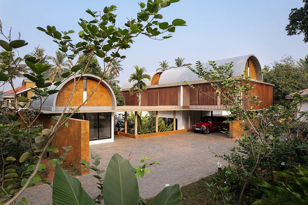 A modern, tropical-inspired building with arched entrances, wooden screens, and lush vegetation.