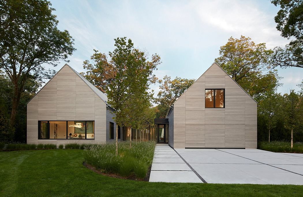Contemporary twin-gabled houses with muted wood siding and large windows amidst greenery