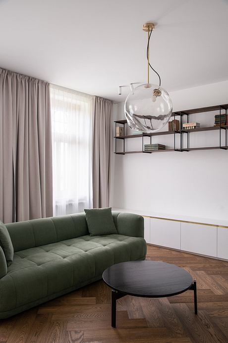 Modern living room with a green sofa, black coffee table, and a large glass