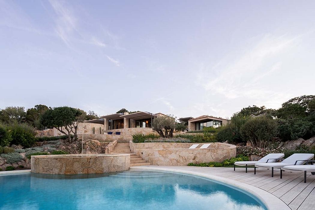 Contemporary stone villa overlooking a curvy pool with lounge chairs.