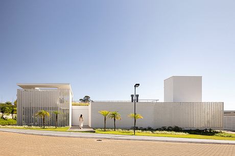 Modern architectural design with clean lines, textured facade, and palm trees.