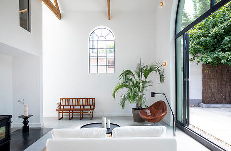 Bright, airy space with arched window, wooden beams, and modern furnishings.