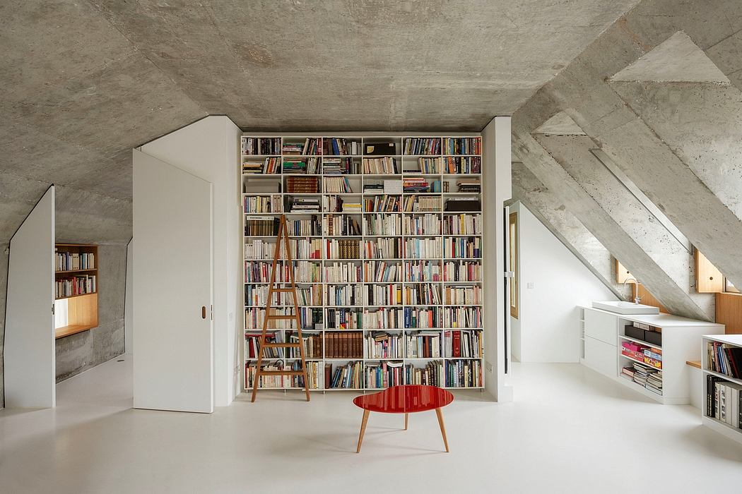 A spacious, minimalist attic with a floor-to-ceiling bookshelf, wooden furnishings, and concrete walls.