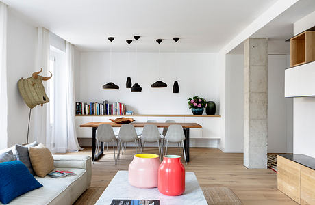 Modern living room with dining area, white walls, and wooden floors.