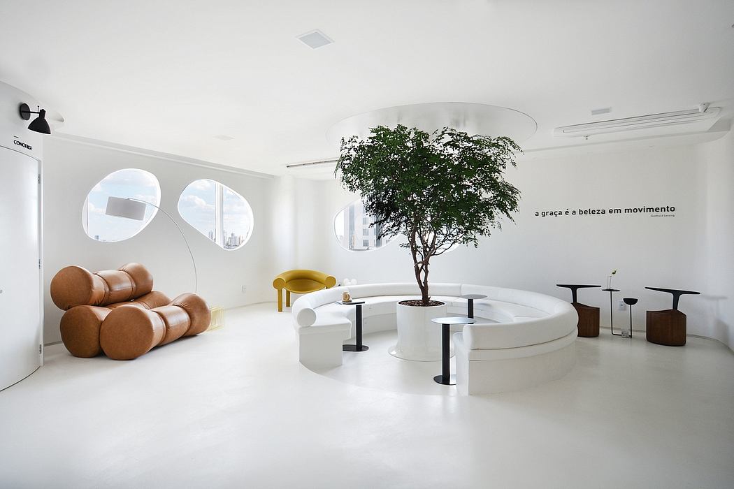 A minimalist, modern interior with curved seating, tree, and circular tables.