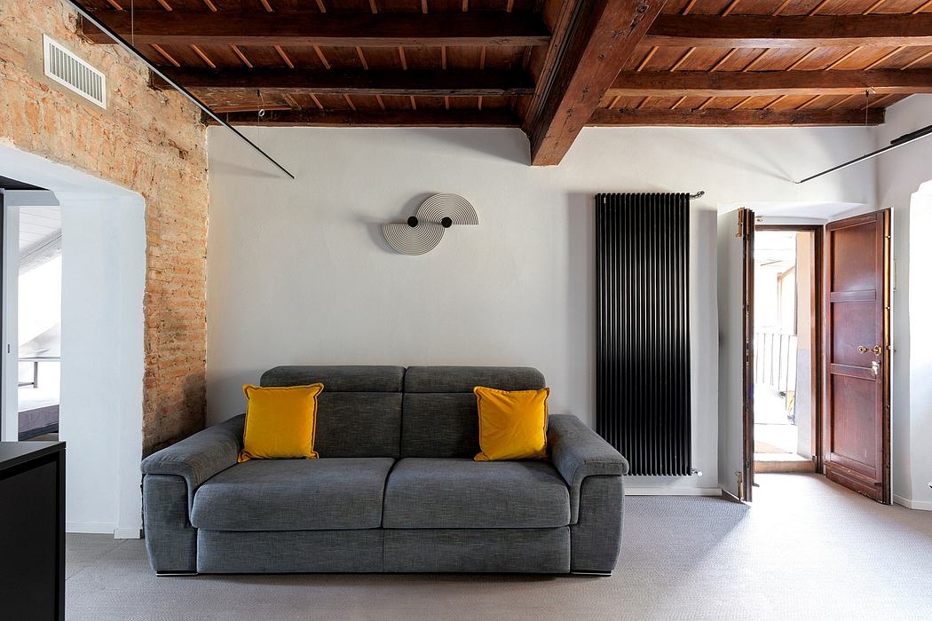 Cozy loft-style living room with exposed brick walls, wooden ceiling, and sleek gray sofa.