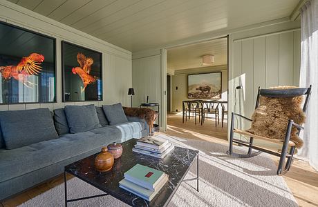 Cozy living room with modern furniture and wooden walls.