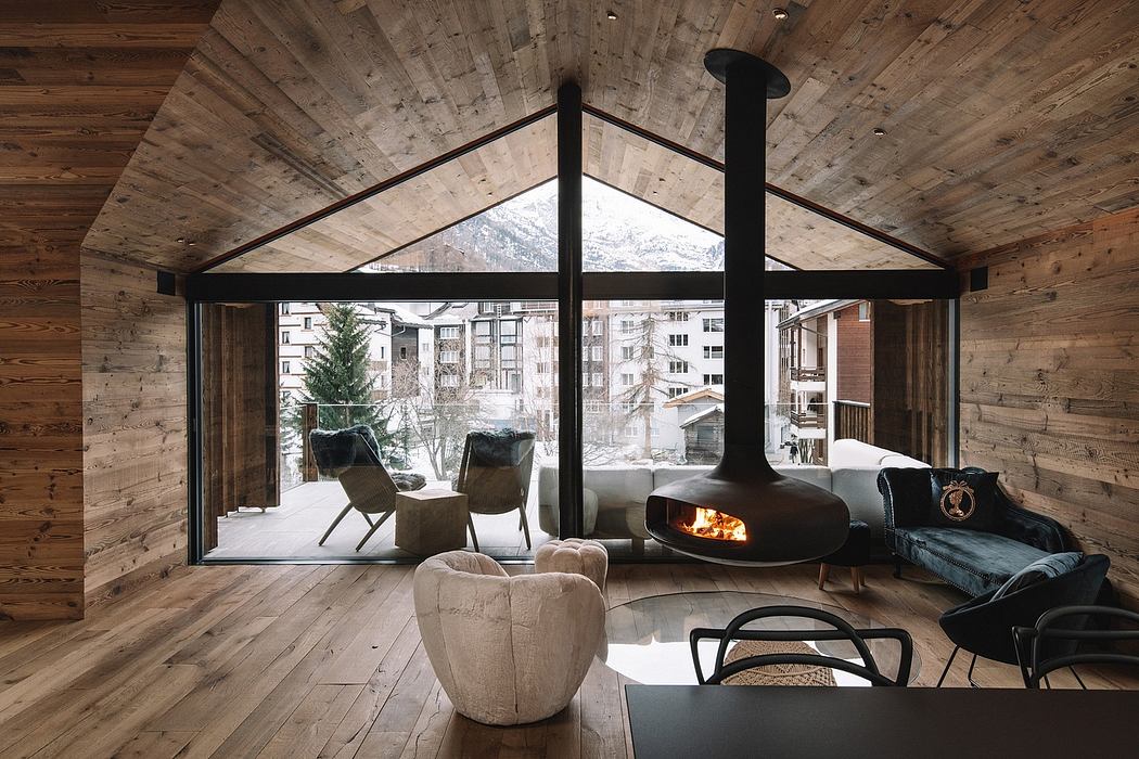 A cozy cabin with wooden walls, a fireplace, and large windows overlooking a snowy landscape.