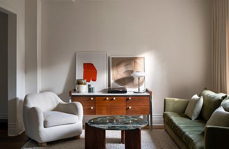 Elegant living room with white armchair, green sofa, and wooden furniture.