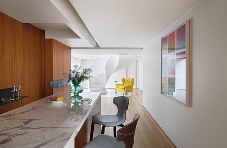 Modern open-concept kitchen with sleek marble countertops, wooden cabinetry, and minimalist furnishings.