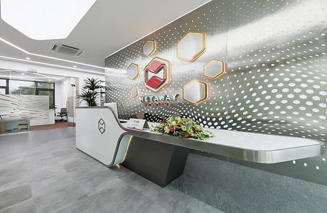 Modern, polished corporate reception desk with geometric shapes and a floral arrangement.