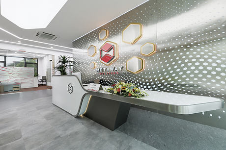 Modern, polished corporate reception desk with geometric shapes and a floral arrangement.