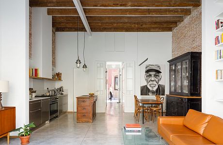 Modern living room with exposed beams, orange sofa, and mural of a man's