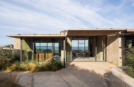 Contemporary stone house with large windows and flat roof.