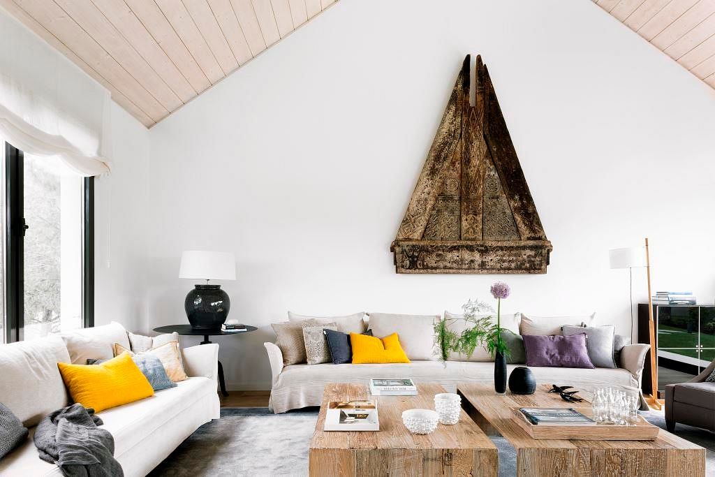 Modern living room with white sofas, yellow accents, and a unique triangular artwork.