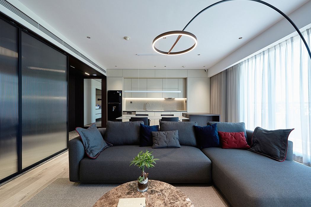 Spacious modern living room with sleek lighting fixtures, grey sofa, and open kitchen layout.