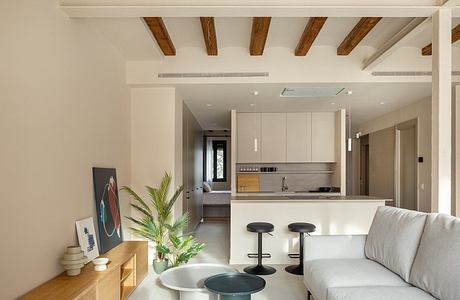 Neutral-toned contemporary living space with exposed wooden beams and modern furniture.