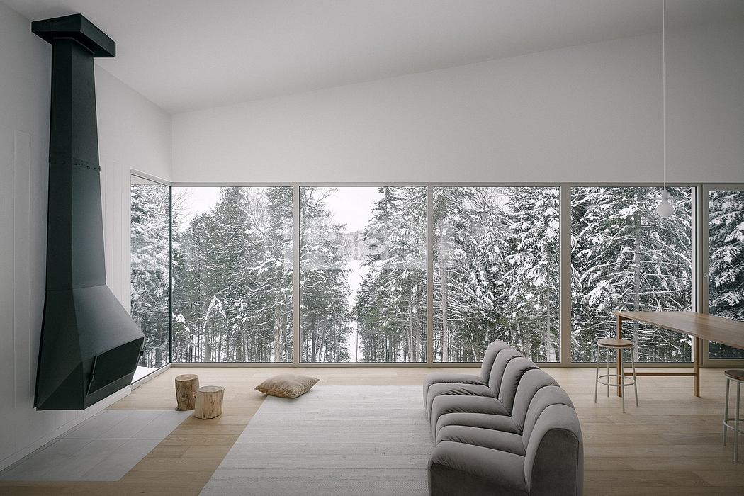 Minimalist living room with large windows overlooking snowy trees.