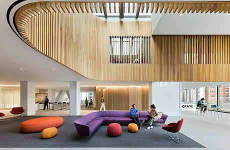 Striking wooden slat ceiling curves above vibrant color-blocked lounge seating.