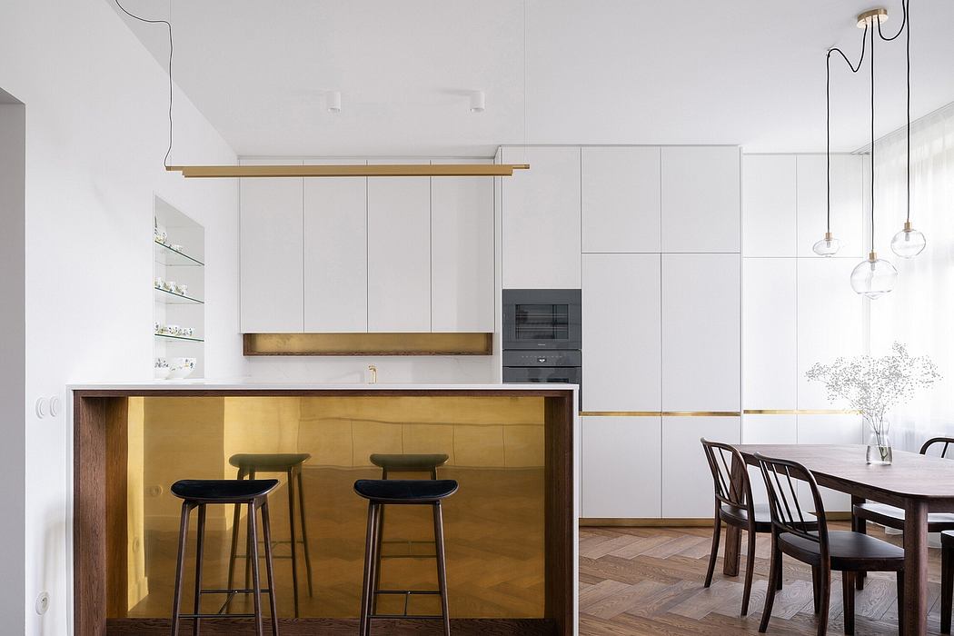 Minimalist kitchen with brass island, herringbone floor, and pendant lights.