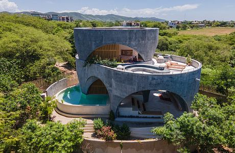 Circular concrete structure with wood accents, pool, and terraced exterior surroundings.