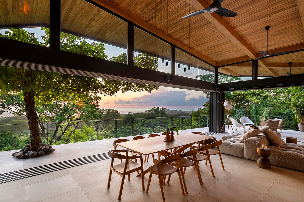 A modern room with large windows overlooking a sunset and nature.
