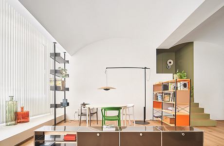 Modern room with white walls, wooden floor, and colorful furniture.