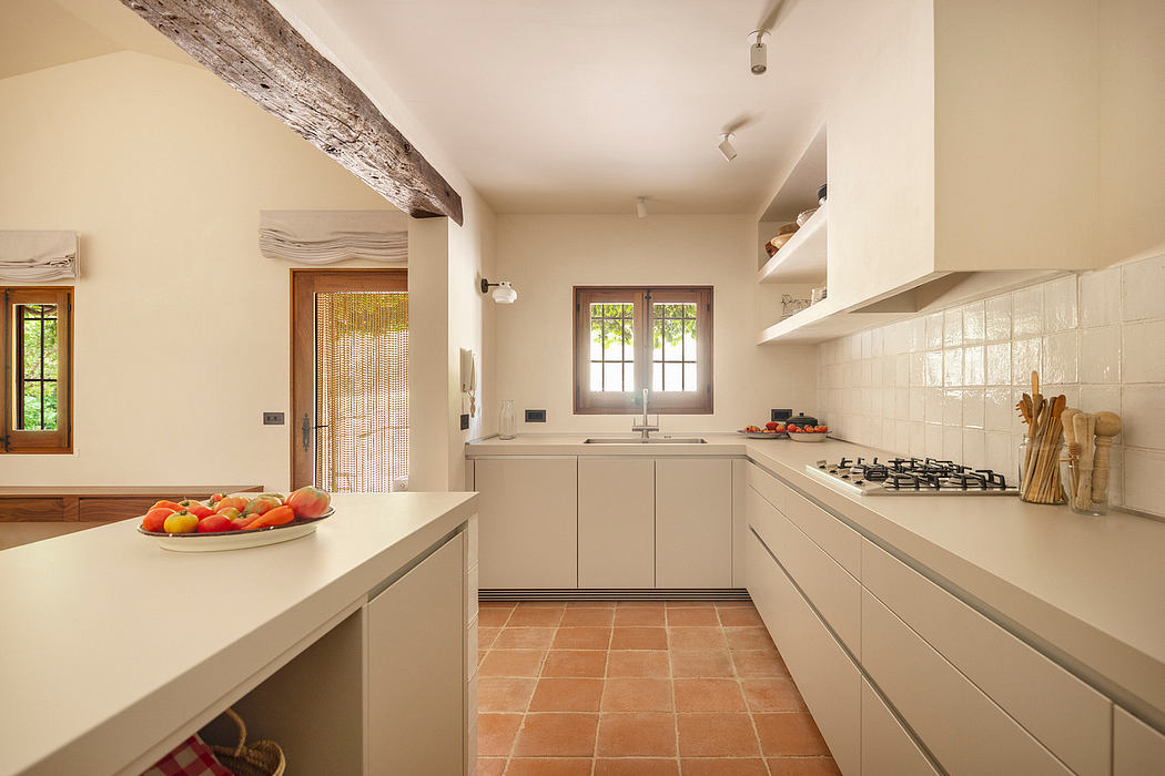 Cozy kitchen with wooden beams, neutral tones, and terracotta tile flooring.