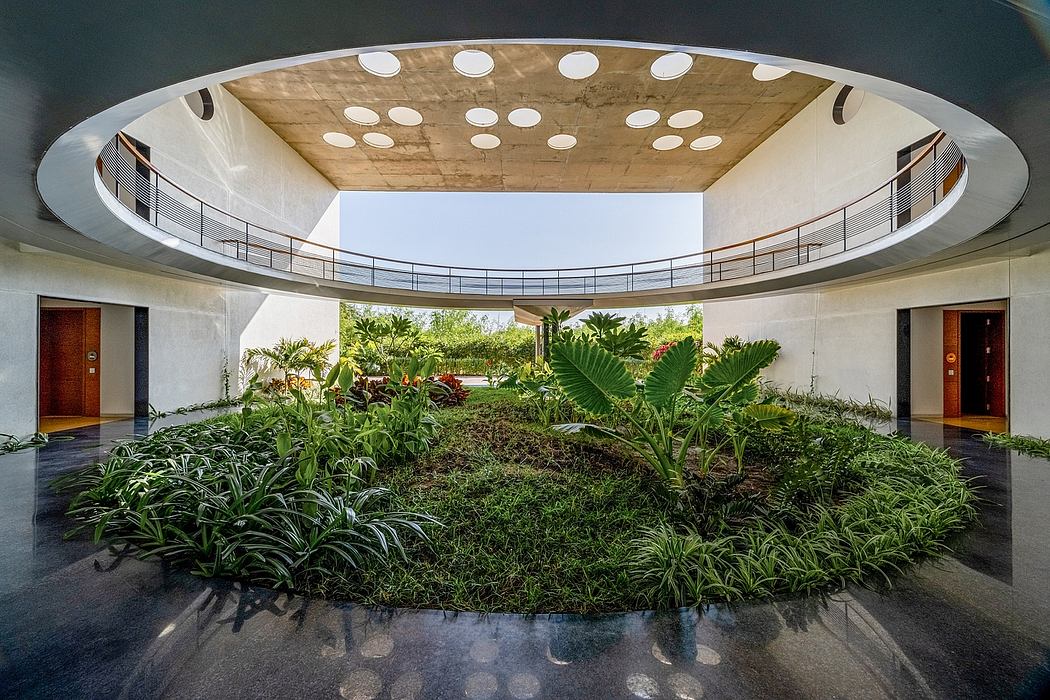 Circular atrium with lush tropical plants and reflective floor in modernist building.