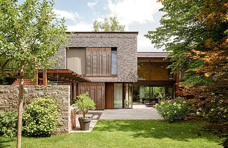 Contemporary house with wooden slats, glass facade, and green lawn.