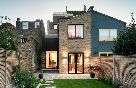 Contemporary house with a brick facade and backyard garden at dusk.