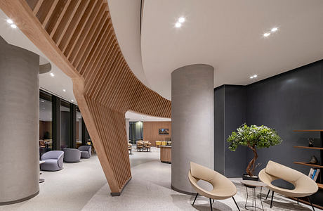 Modern interior with curved wooden staircase, concrete pillars, and elegant furniture.