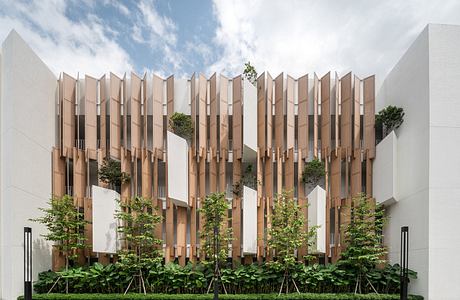 Modern building facade with vertical wooden fins and integrated greenery.