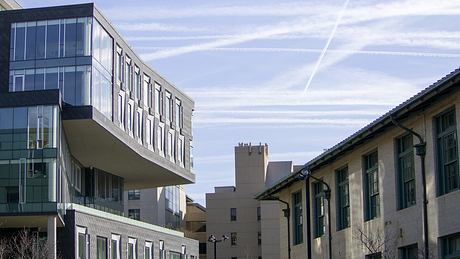 Contemporary building with cantilevered section over traditional structures.