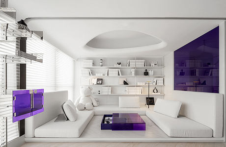 A modern living room with minimalist white furniture, purple accents, and built-in shelving.