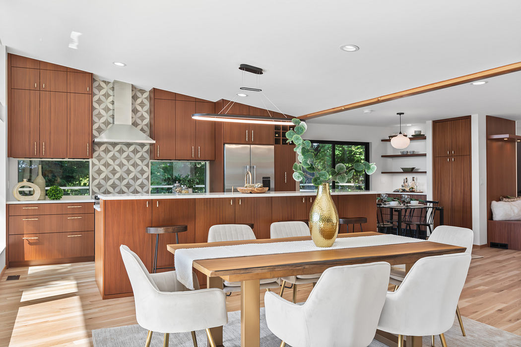 Modern kitchen and dining area with wood cabinetry, geometric tile backsplash, and gold accents.
