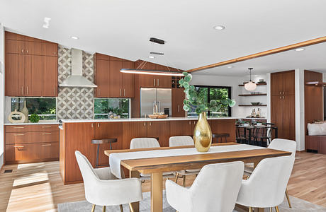 Modern kitchen and dining area with wood cabinetry, geometric tile backsplash, and gold accents.