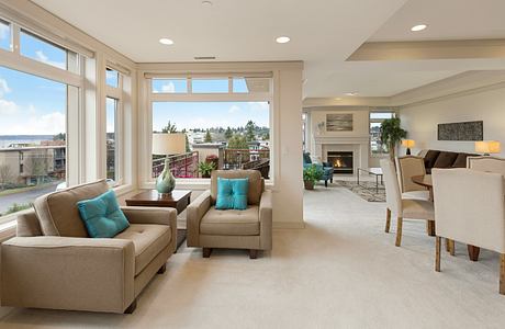 Spacious open-concept living area with large windows, plush seating, and a fireplace.