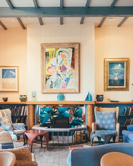 Cozy room with eclectic furniture, a fireplace, art pieces, and booksh