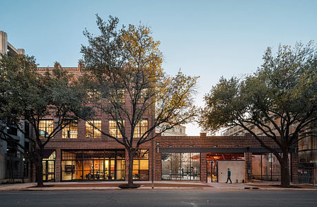 Brick building with large glass windows surrounded by trees in autumn foliage.