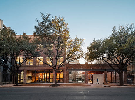 Brick building with large glass windows surrounded by trees in autumn foliage.