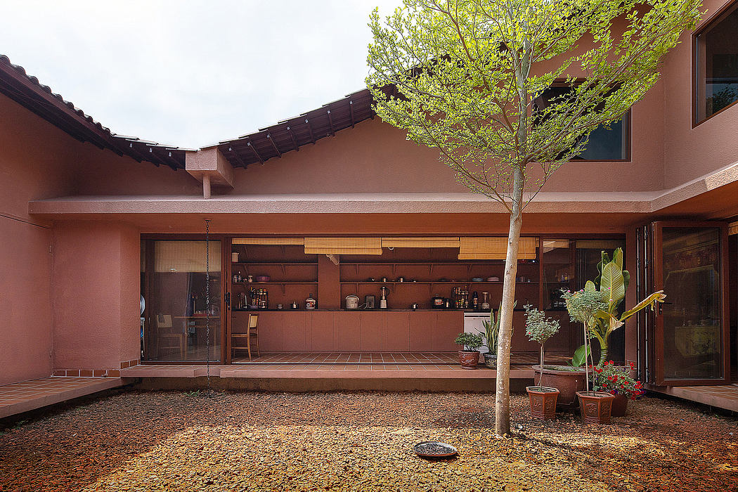 Warm-toned adobe architecture surrounds an open courtyard with a central tree.