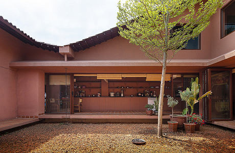 Warm-toned adobe architecture surrounds an open courtyard with a central tree.