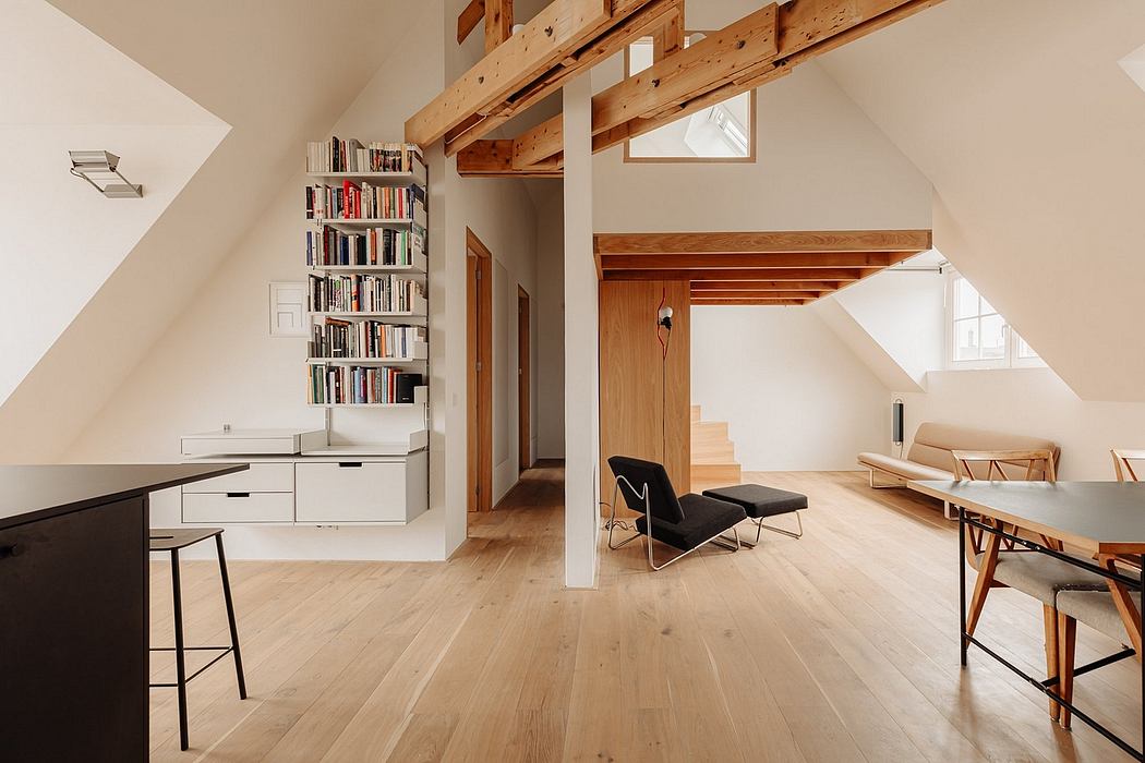 Airy loft space with exposed wooden beams, built-in bookshelf, and minimalist furnishings.