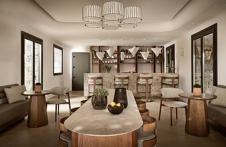 An elegant, modern dining area with a concrete dining table, plush seating, and a striking chandelier.