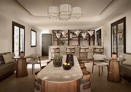 An elegant, modern dining area with a concrete dining table, plush seating, and a striking chandelier.